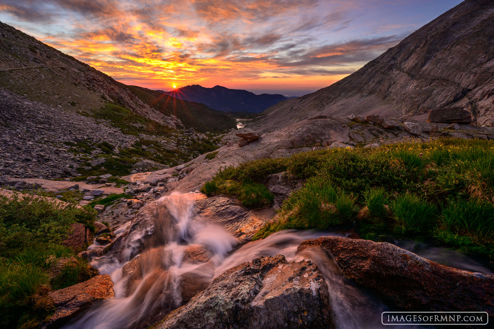On a summer morning in Rocky Mountain National Park, the warm light of the rising sun gently awakens the world as the rushing...